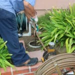 a plumber clearing a main sewer line clog