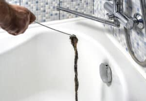 a man unclogs a bathtub drain