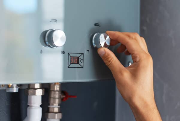 a man quickly and easily adjusts the temperature on his interior wall-mounted tankless water heater